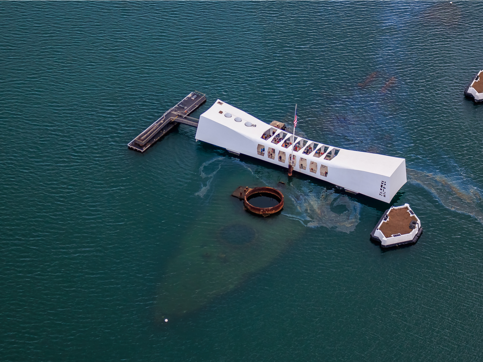 Aerial view of sunken USS Arizona Memorial, one of the most iconic places in America, in the Pacific National Monument in Pearl Harbor Honolulu Hawaii where a small amount of oil can be seen on water surface