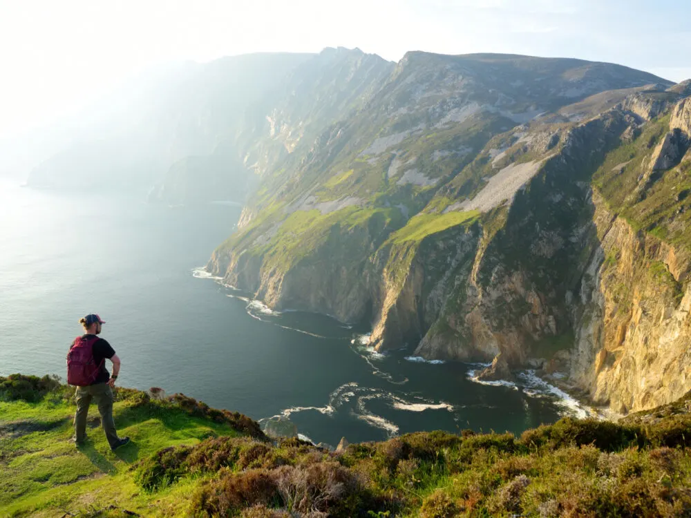 Slieve League with a man looking over the cliffs and ocean during the worst time to visit Ireland