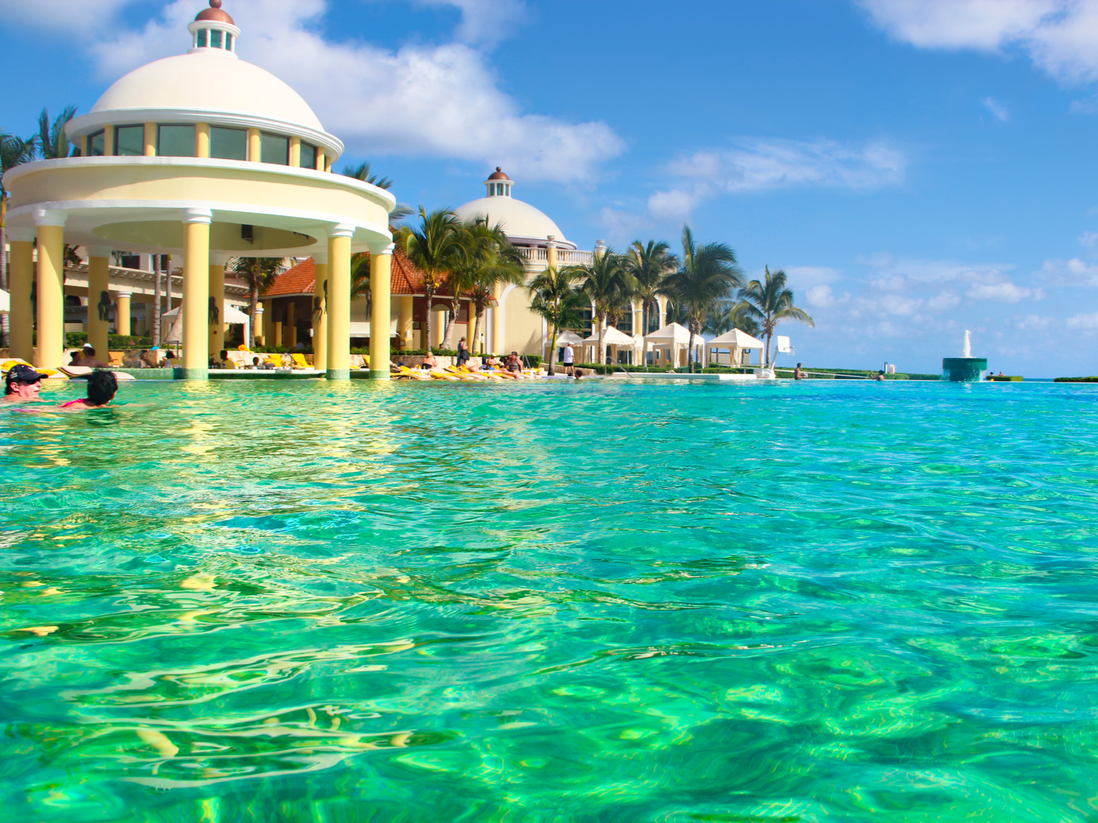 Tourist swimming on the emerald salt pool and others enjoying the sun on the poolside at Iberostar Grand Paraiso, known as one of the best all-inclusive resorts in Mexico