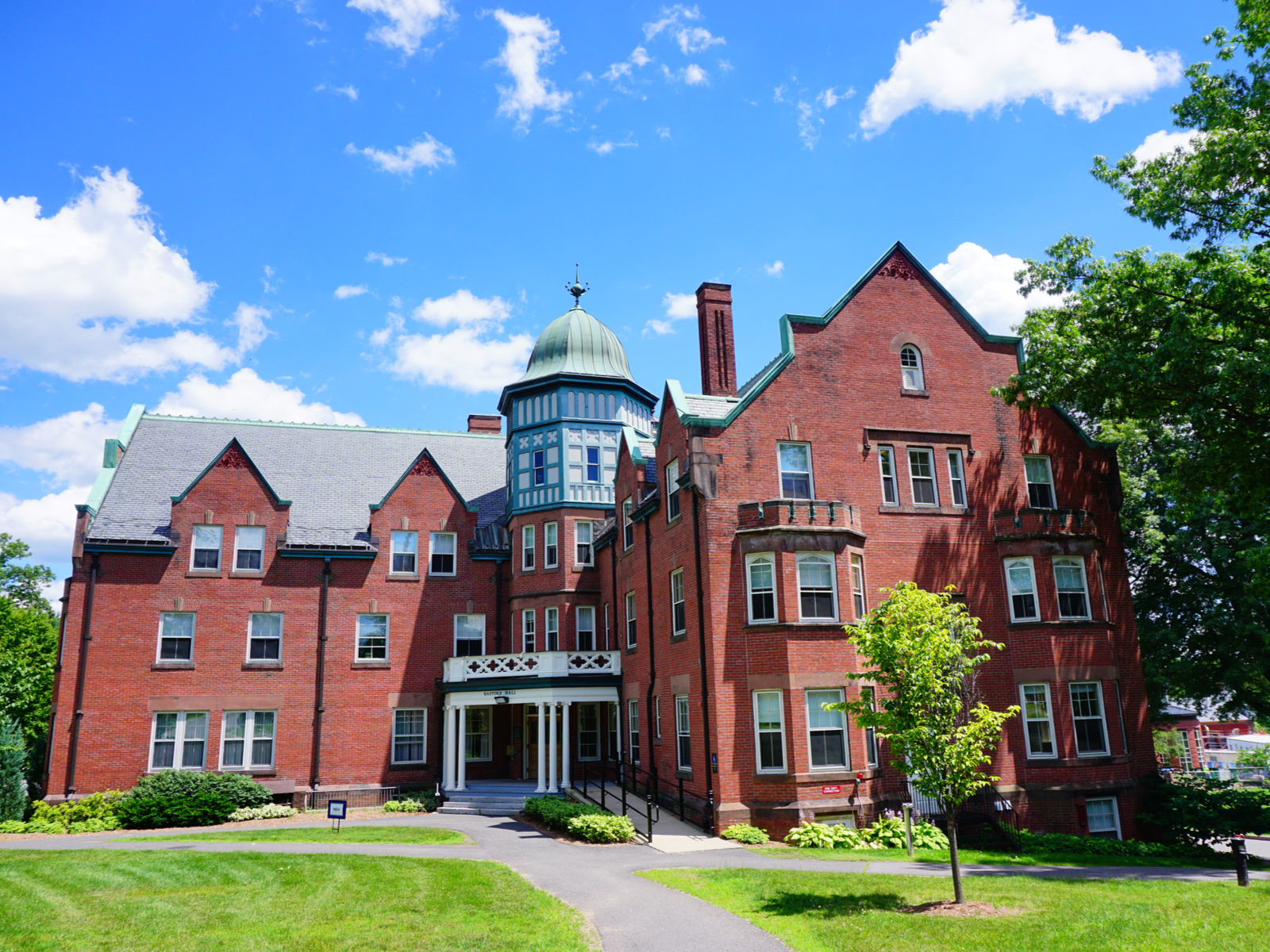An old red colored building fronting a green lawn at Mount Holyoke College in Massachusetts, one of the most beautiful college campuses