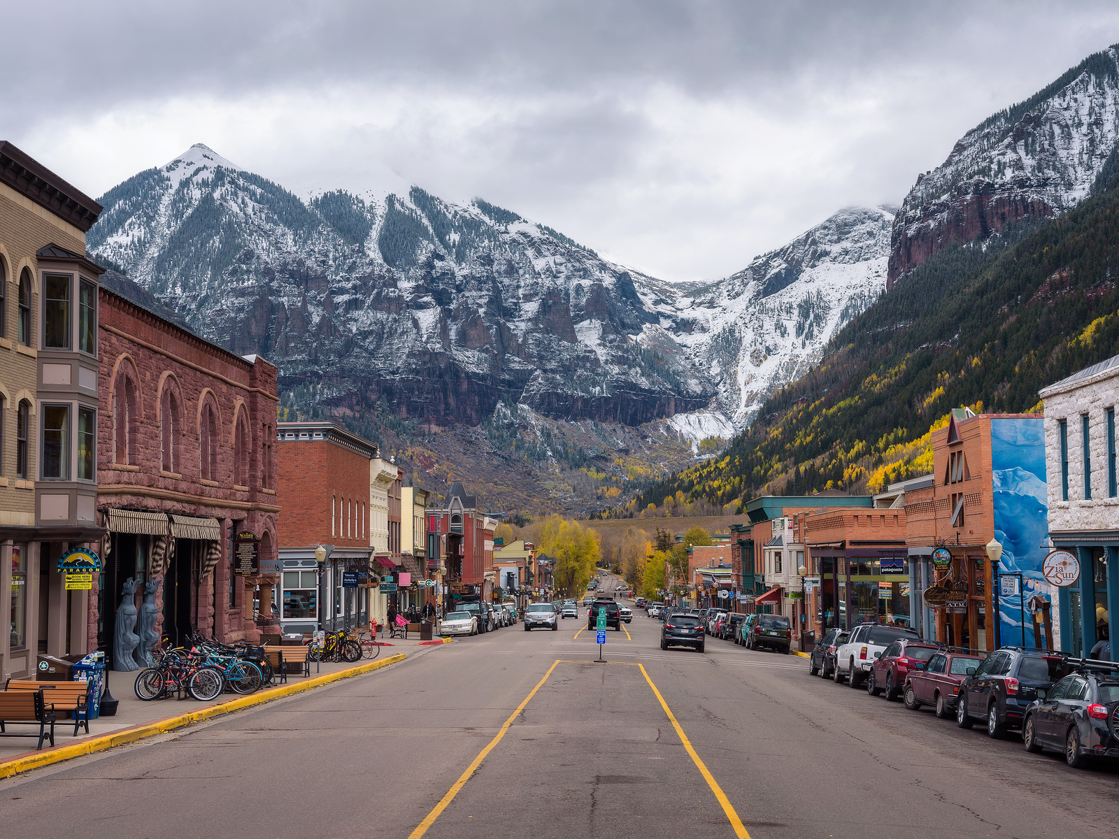 Cars parked on the street side with historic structures of Telluride, Colorado, one of the most beautiful cities in the US, at the foot of the snowy San Joan Mountains