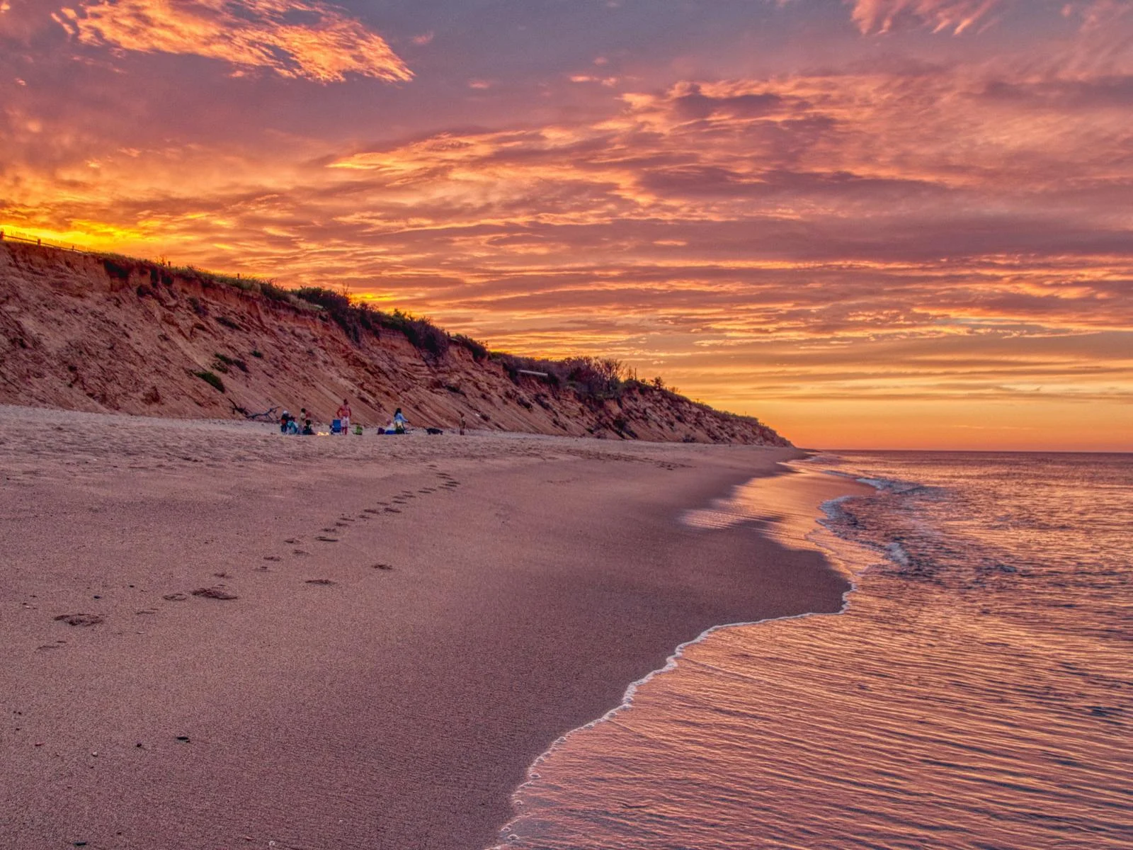 A group of friends relaxing on a golden sunset by the shore of Cape Cod National Seaside in Massachusetts, one of the best beaches on the East Coast