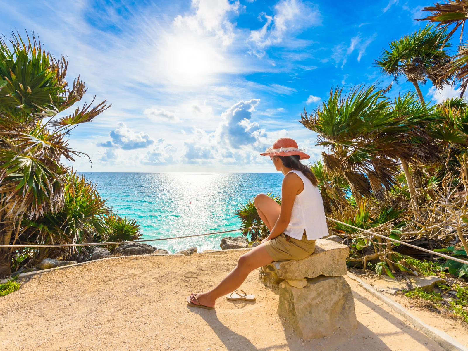 Woman relaxing on a rock overlooking the ocean during the best time to visit Tulum