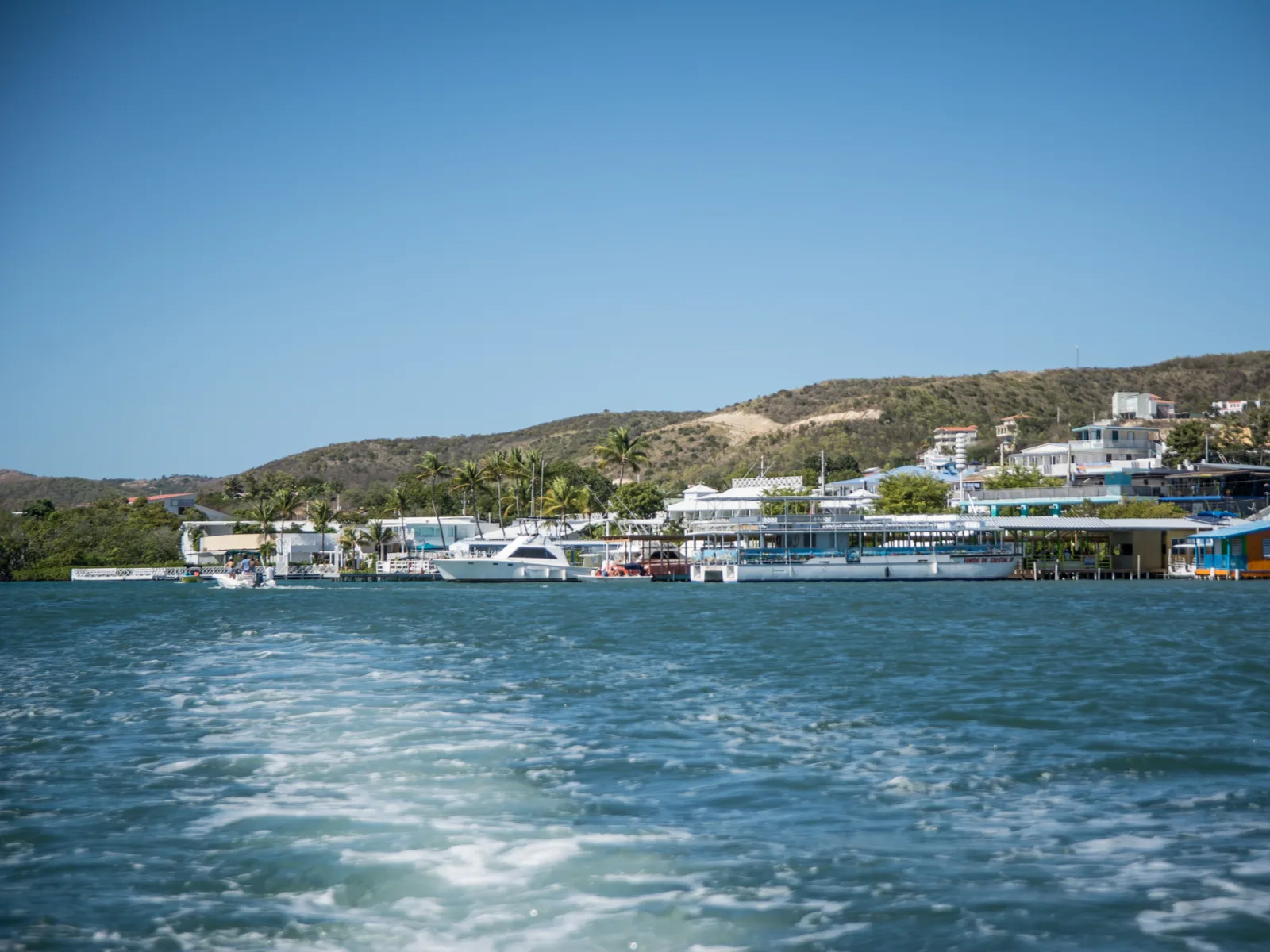 Boats docked beside homes on the water at the small paradise of La Parguera, photographed from a sailing ship for a piece on the best places to visit in Puerto Rico