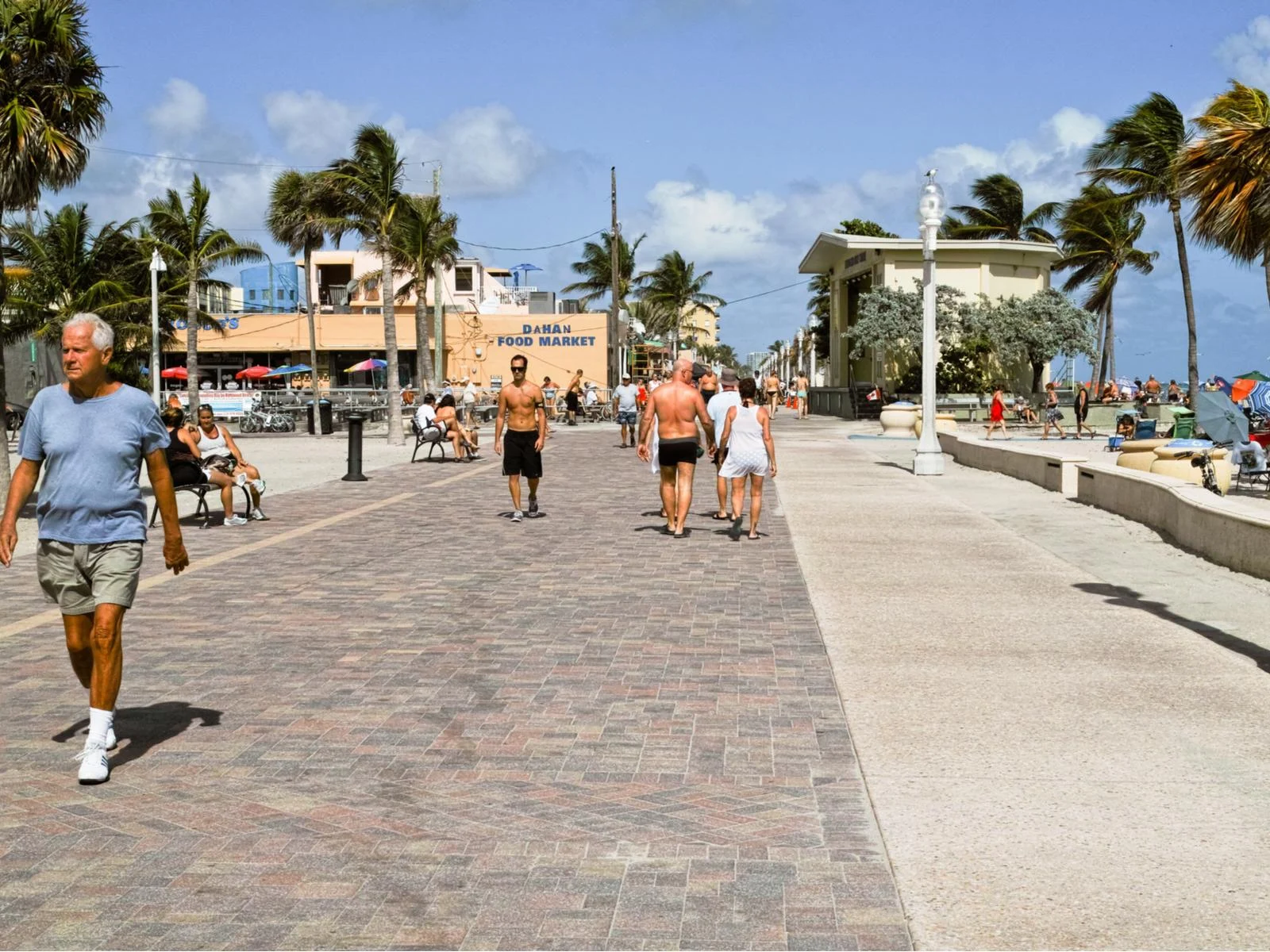 Several tourists on the Hollywood Beach boardwalk on a sunny day for a piece on the best things to do in Fort Lauderdale