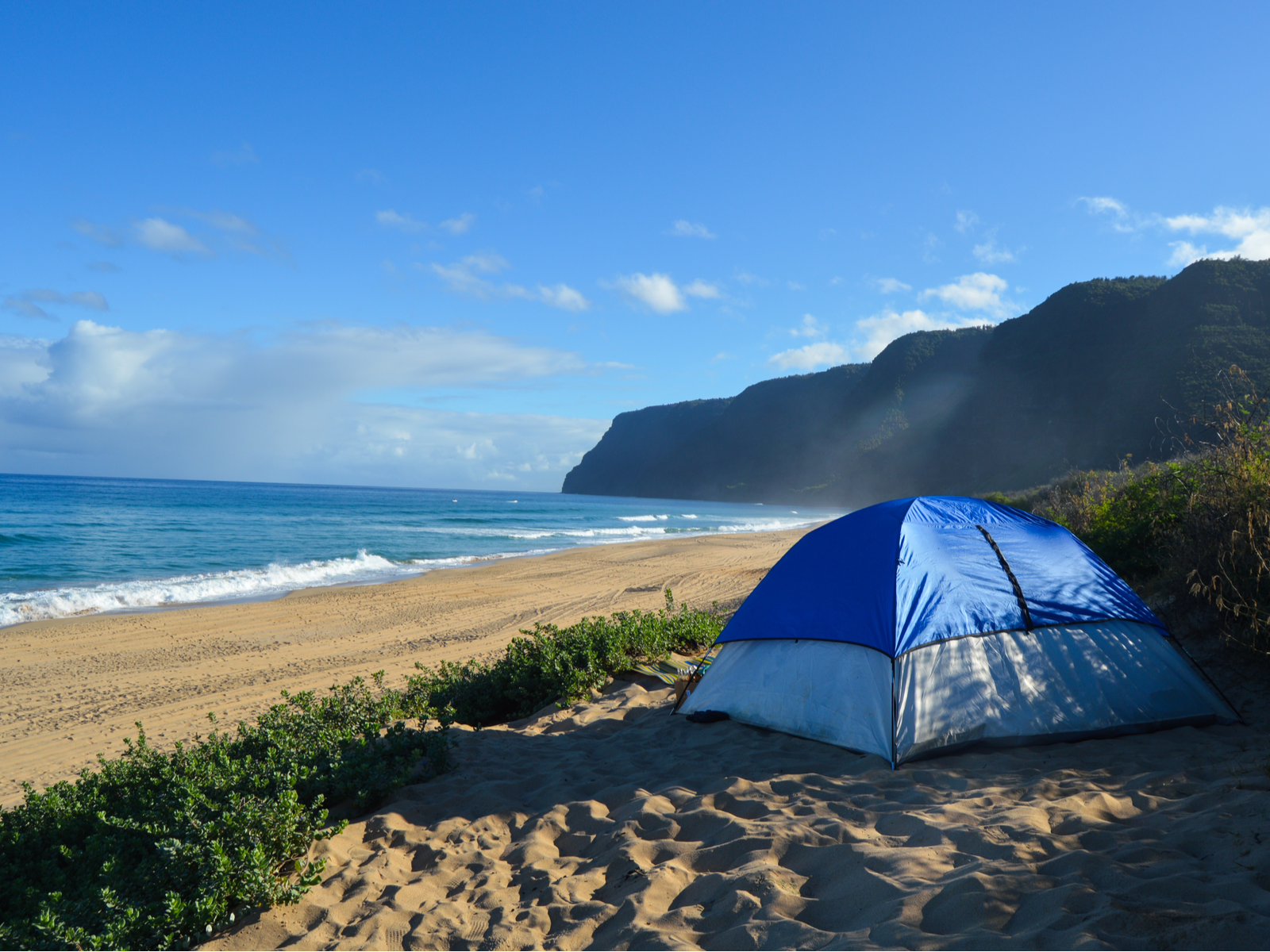 A tent set up on the shore at Polihale Park, camping here is one of the best things to do in Kauai with the scenic tropical beach view