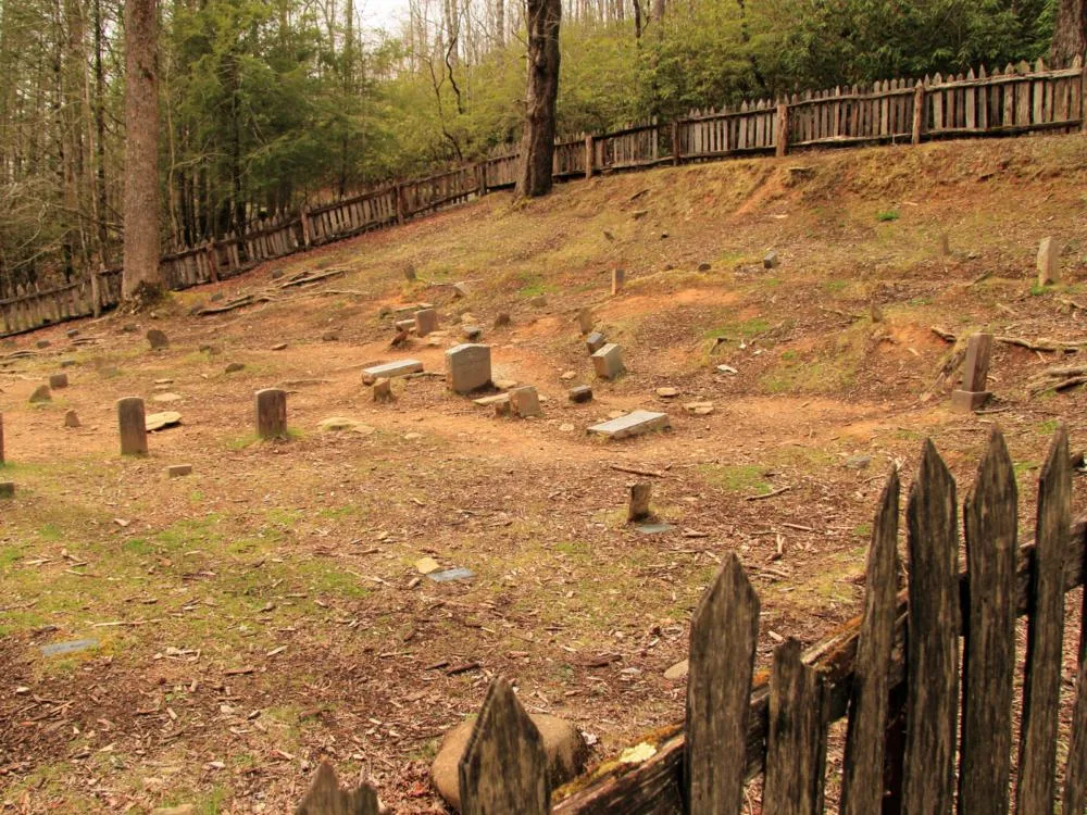 an old cemetery for a ghost tour, one of the best things to in gatlinburg, tennessee, is surrounded by huge and tall trees, and old looking wooden fence