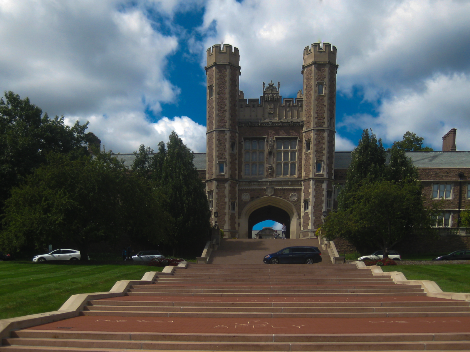 Cars passing by a road intersecting a stairs in front of a historic structure at Washington University in St. Louis in Missouri, named as one of the most beautiful college campuses