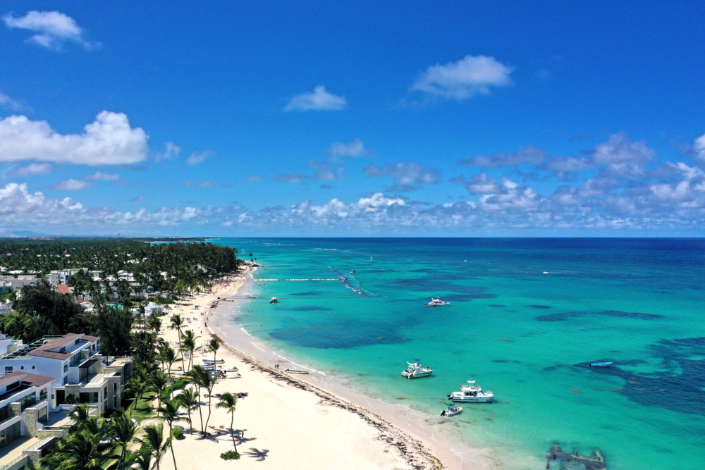 Playa Bavaro aerial view with resorts on the beach and white sand with blue skies overhead for a frequently asked questions section detailing the perfect time to visit Punta Cana