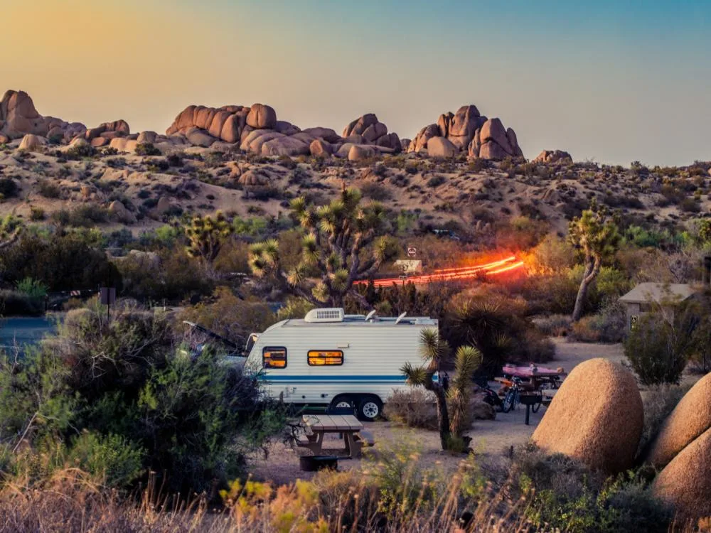 Campers in RV spend the night over a campsite at Joshua Tree National Park, one of the best things to do in California, where distinct rock formations can be seen at a distance