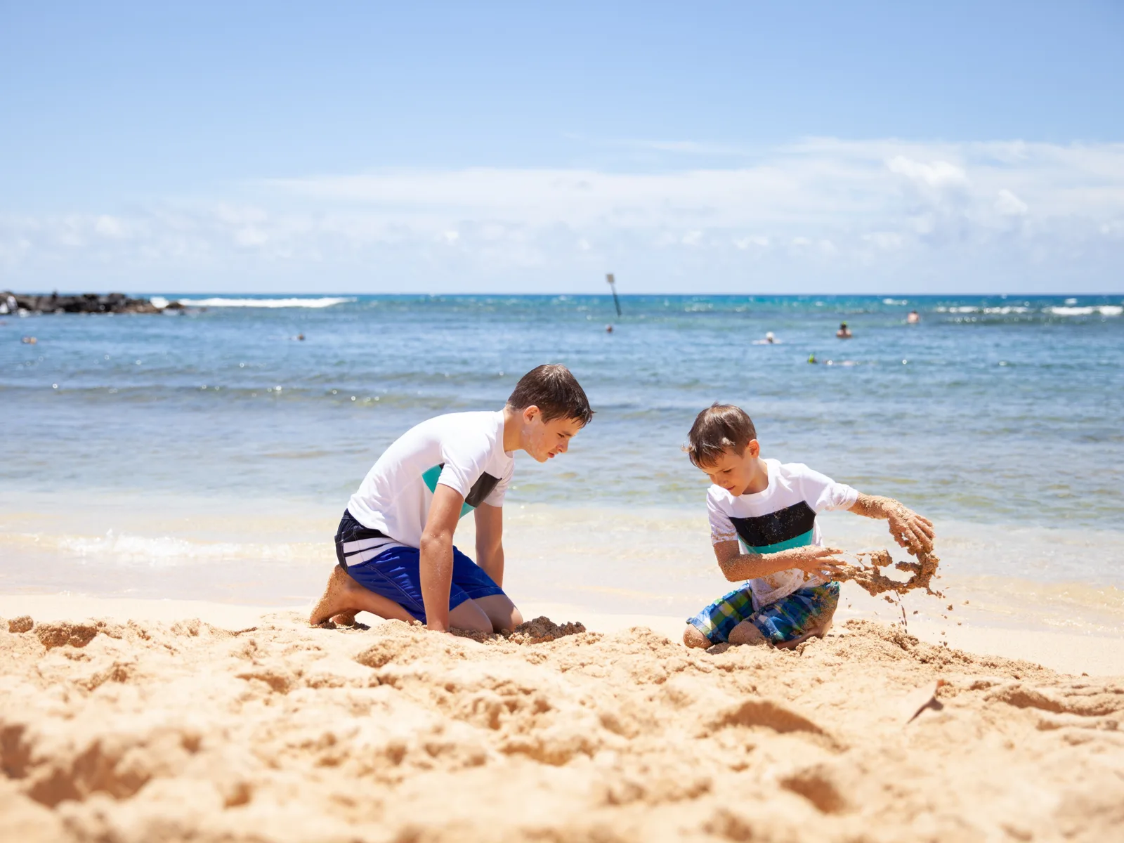Two children, wearing the same shirt, playing with the same at one of the best beaches in Kauai