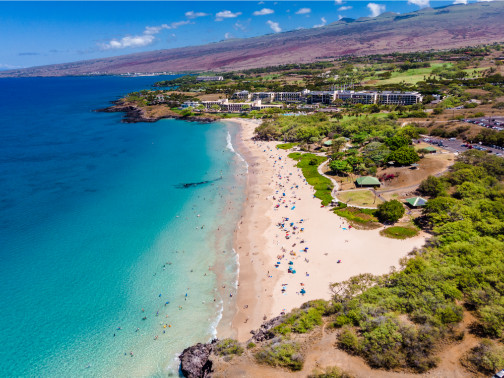 Aerial view on the crowded shore of Hapuna Beach State Park in Hawaii Big Island, considered as one of the best beaches in the US, where visitors and seen putting belongings on the shores and swimming on the clear sea