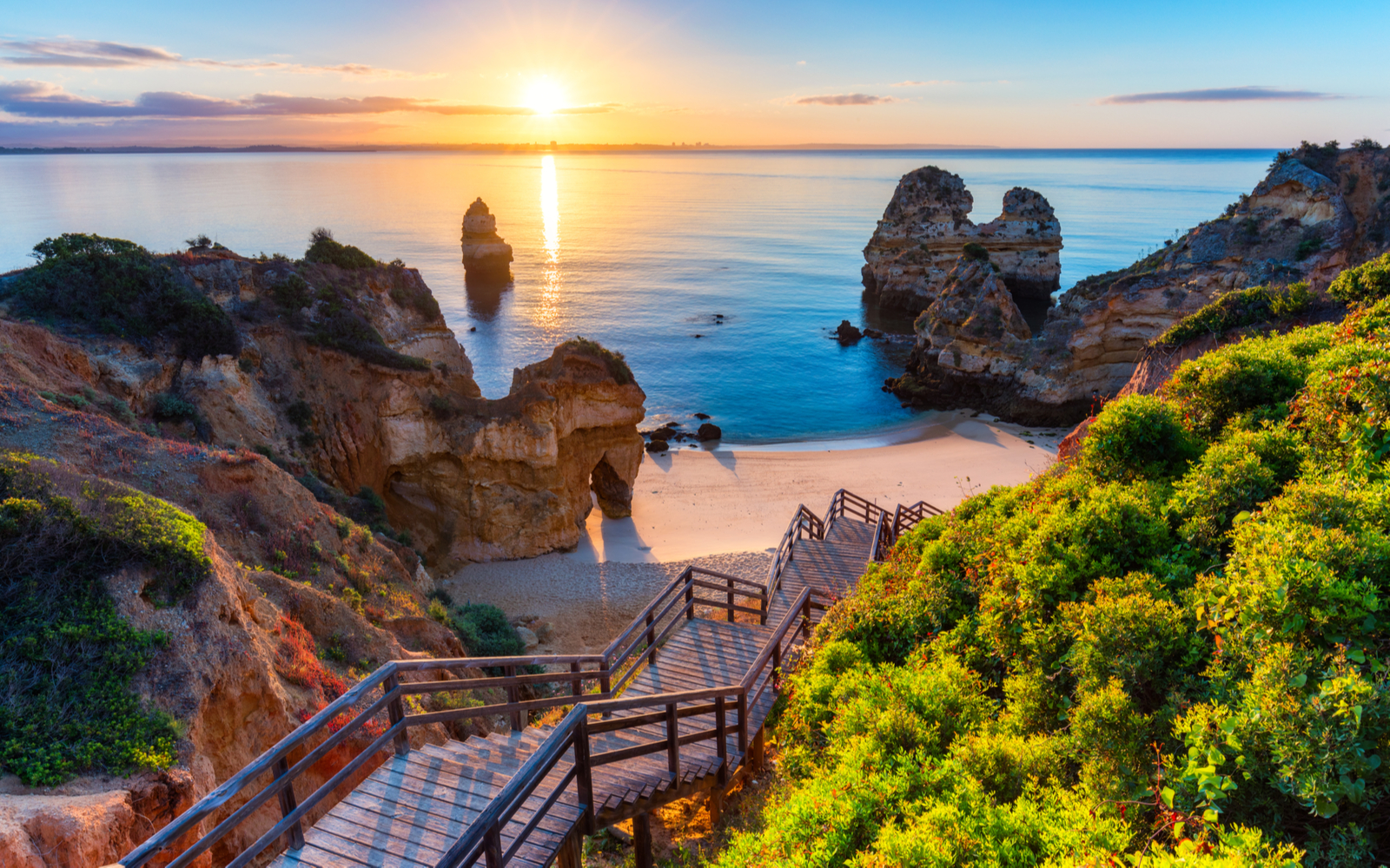 As seen from the top of the stairs, Camilo Beach pictured during the best time to visit Portugal while the sun sets