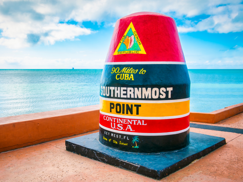 Giant red and black concrete buoy pictured during the best time to visit Key West, when the sun is out with limited cloud cover and warm water