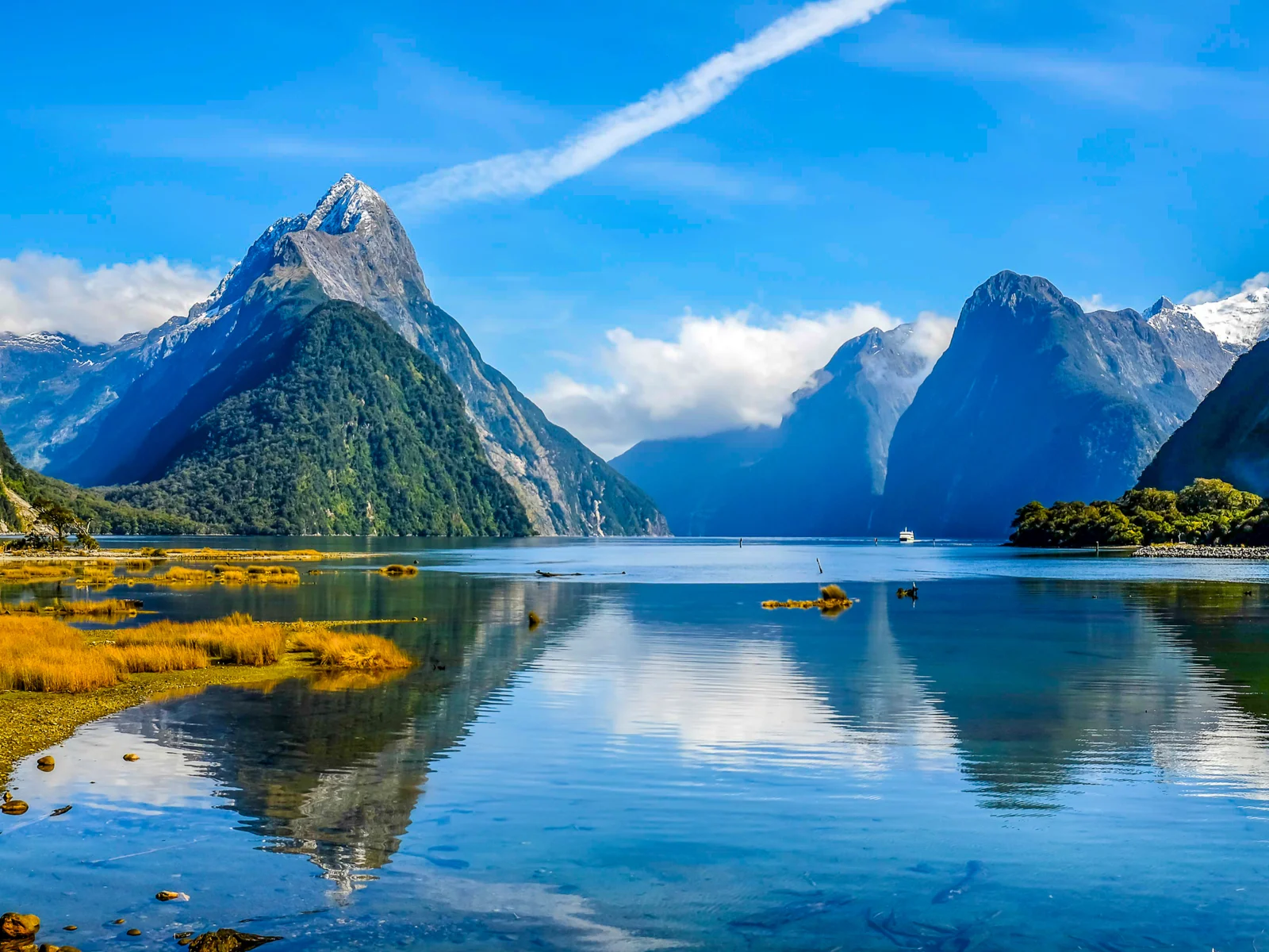 A dreamy Lord of the Rings filming locations, nearly still clear waters and tall snowy peak mountains of Fjordland National Park