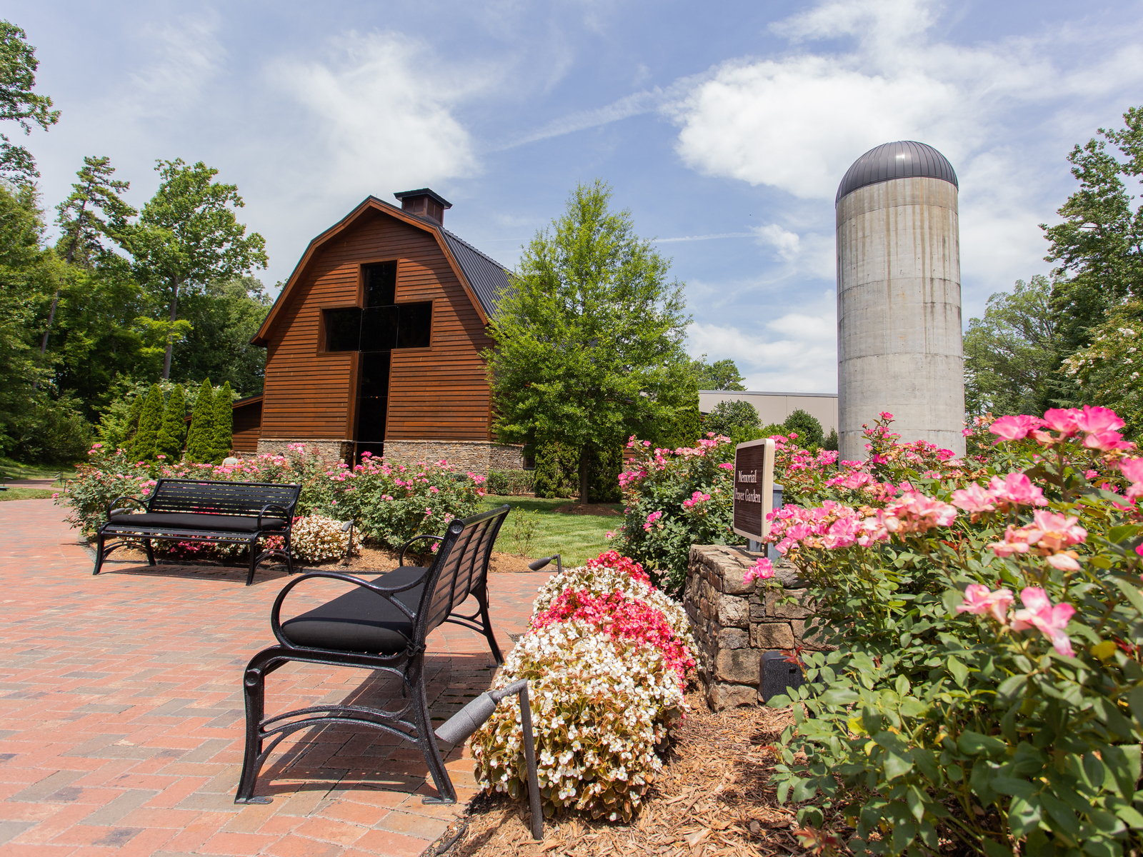 the remarkable sturdy-looking wooden billy graham library is one of the best things to do in charlotte, nc, with cross design and two metal bench sitting in front