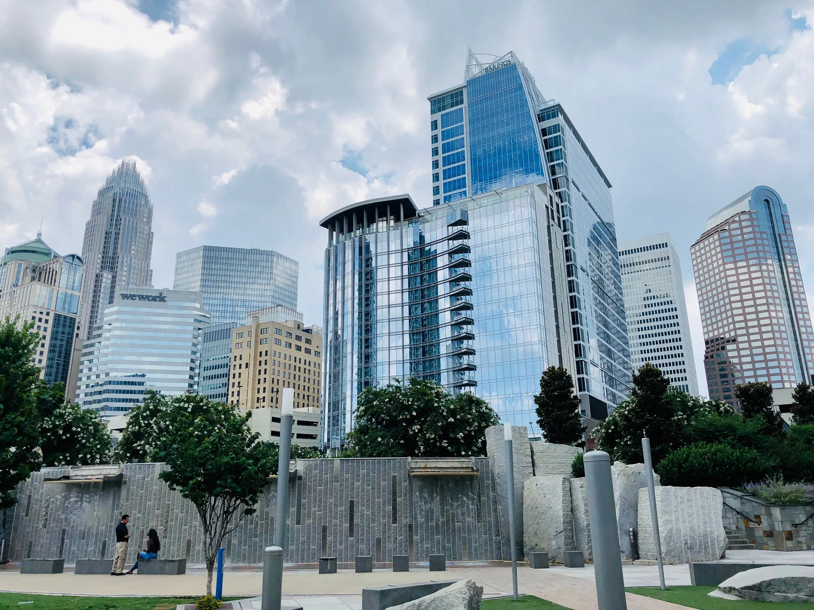 a couple having a conversation during a sweet day beside the tall buildings of romare bearden park, one of the best things to do in charlotte, nc
