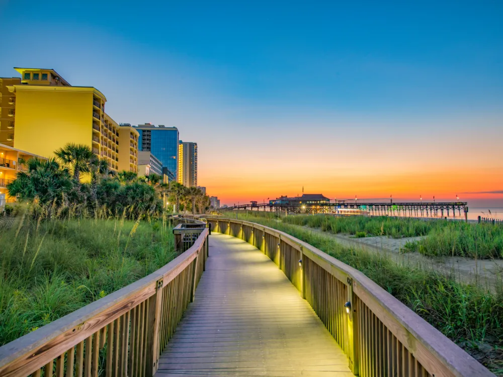 Empty boardwalk leading to various resorts pictured during the least busy time to visit Myrtle Beach with the ocean in the frame off to the right