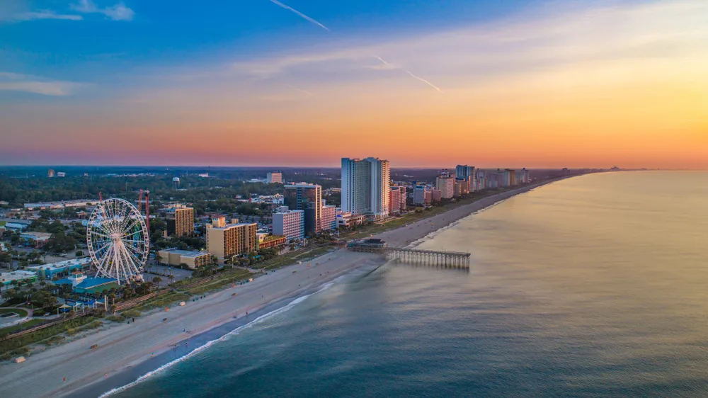 Downtown Myrtle Beach aerial view with the boardwalk and SkyWheel visible at sunset for a guide detailing the best time to visit Myrtle Beach