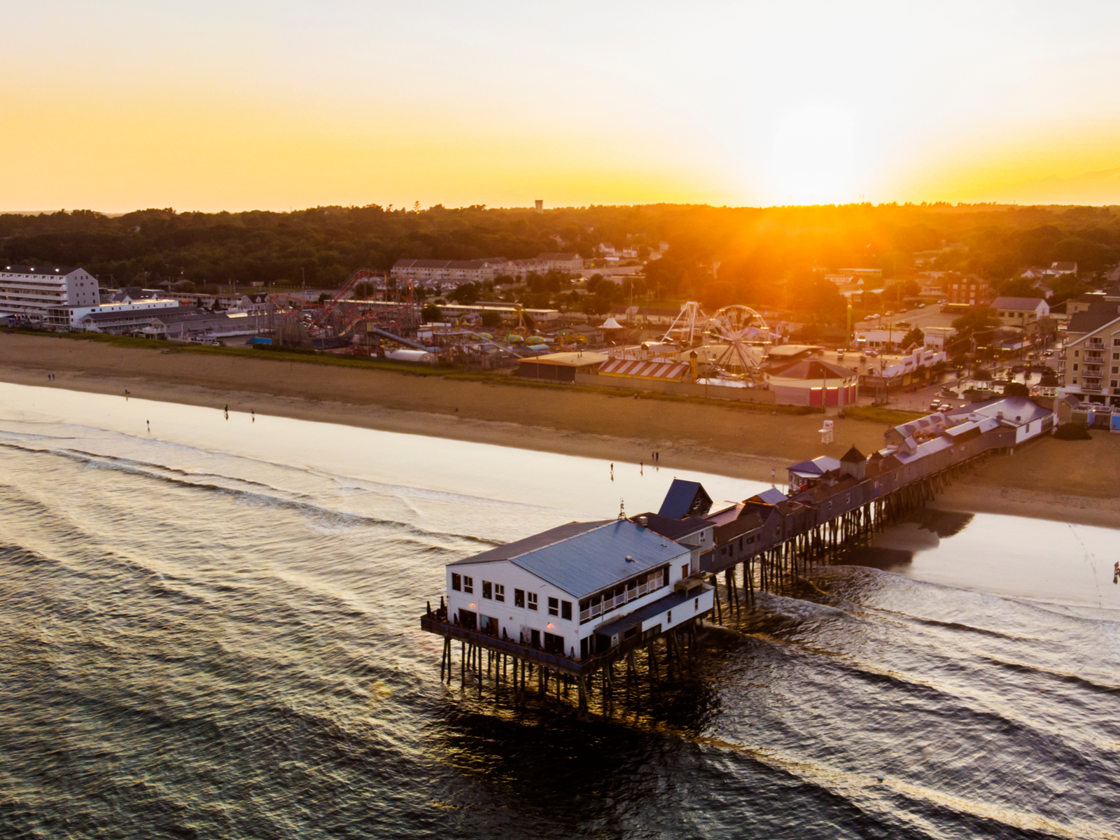 Sunset over the tranquil Old Orchard Beach in Maine, one of the best beaches on the East Coast, with its iconic structures on a boardwalk and a small amusement park offshore