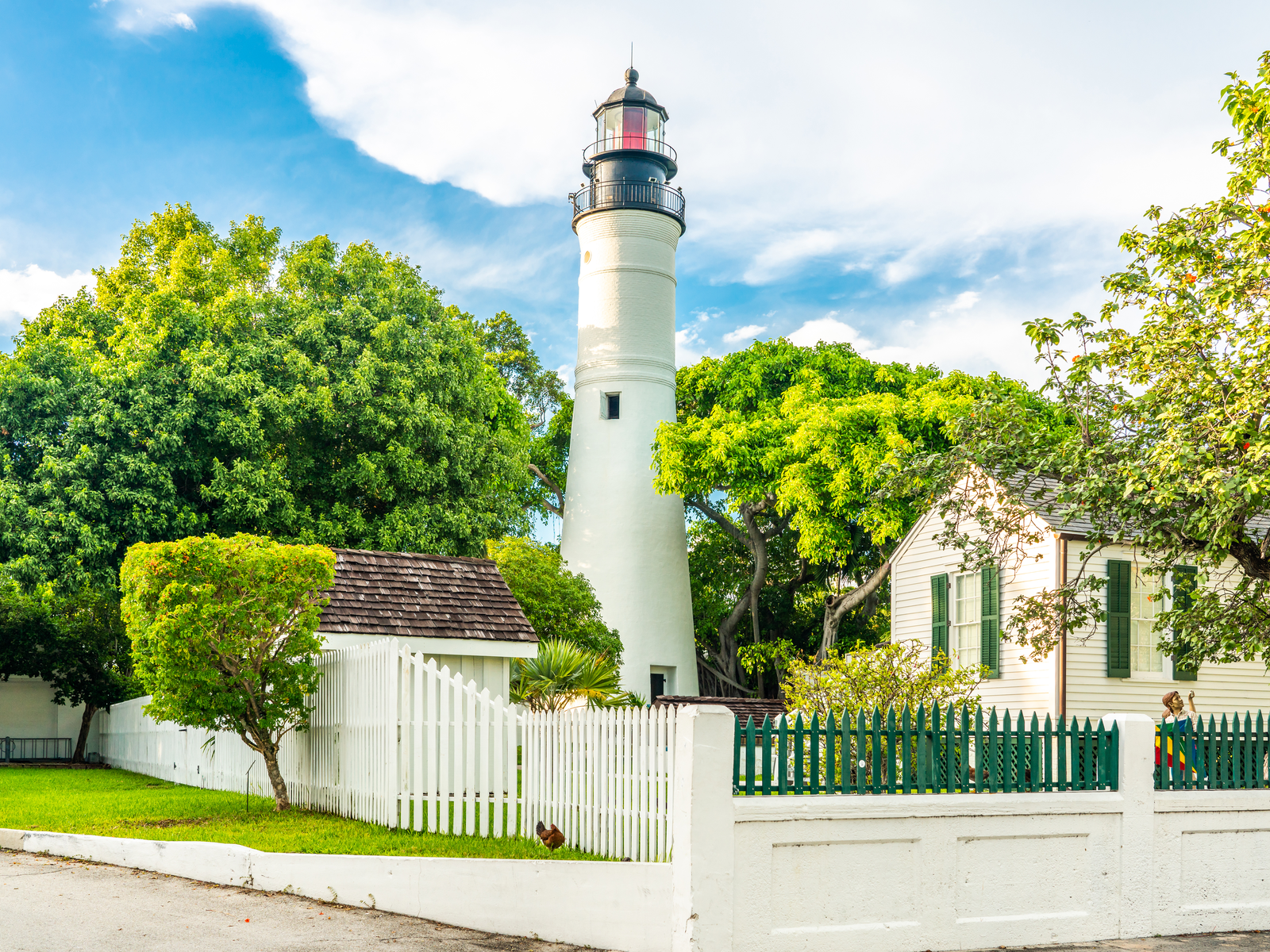 White lighthouse and residential house inside a fenced lot, Key West Lighthouse Museum as one of the best things to do in Key West