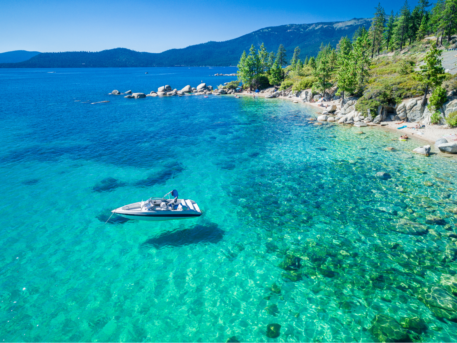 Aerial view of Emerald Bay with a boat that's floating on crystal-clear water for a piece on the best time to go to Lake Tahoe