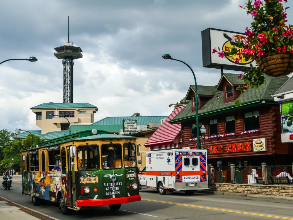 an old gatlinburg trolley, one of the best things to do in gatlinburg, tennessee, and an ambulance in a street near gatlinburg space needle