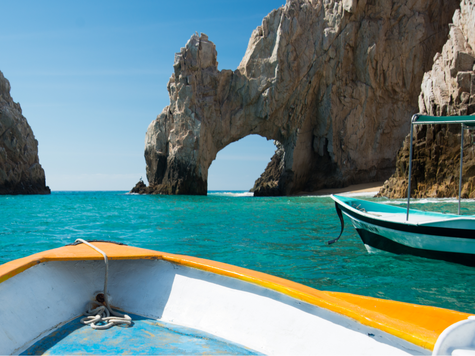 Sunny Lover's Beach and The Arch in front of a boat for a piece on Is Cabo Safe to Visit