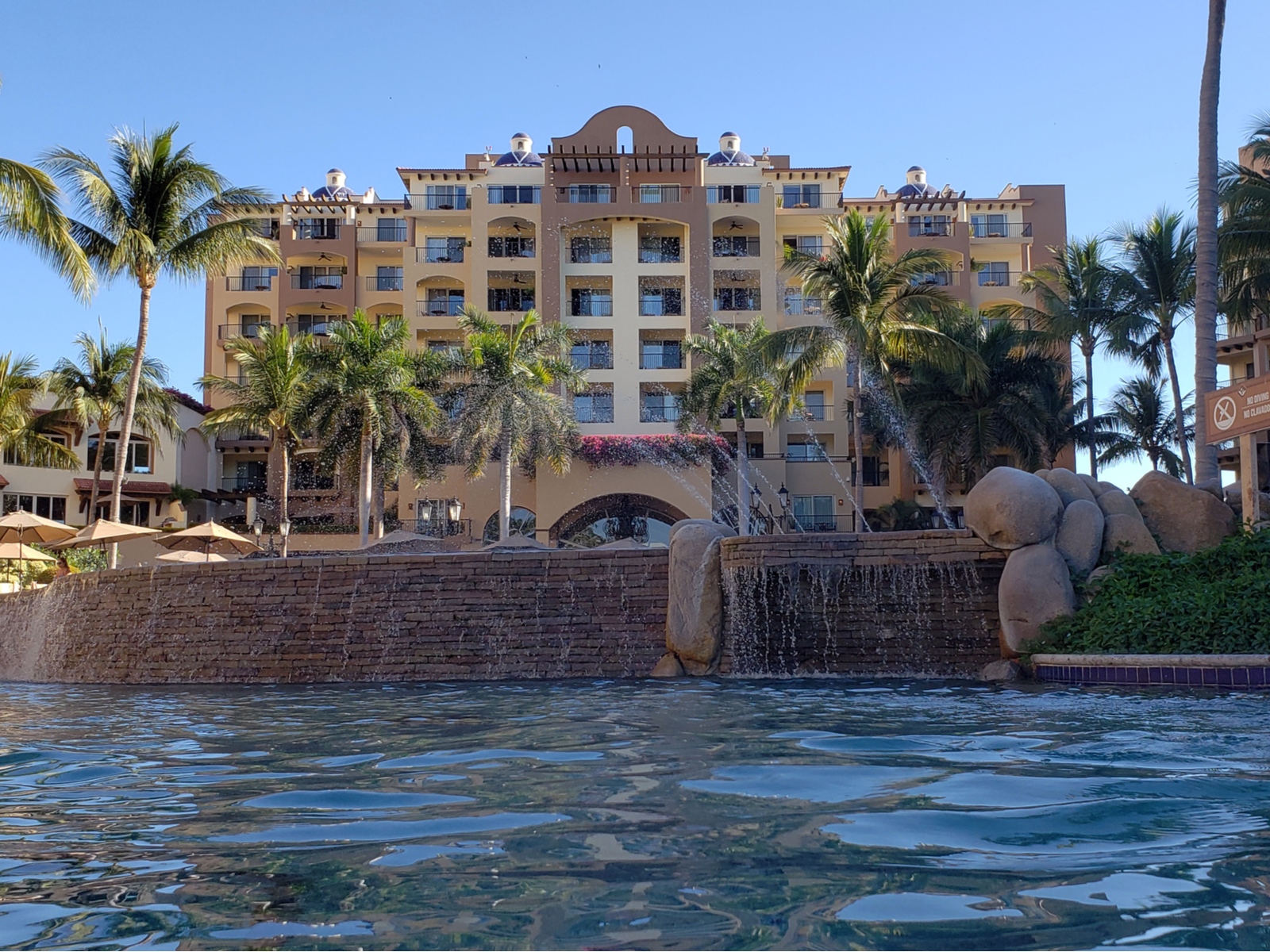 Spouting water on the pool in front of Villa del Palmar Beach Resort & Spa structure with palm trees, a piece on the best all-inclusive resorts in Mexico