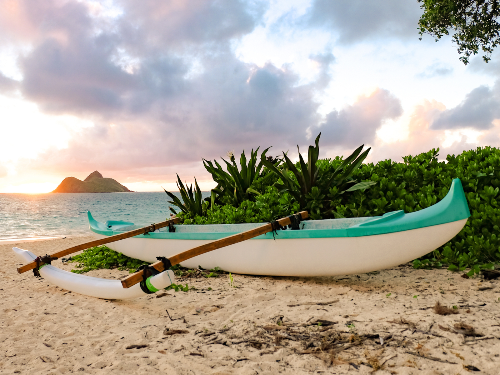 Canoe resting on a tropical beach during sunset during the least busy time to visit Oahu