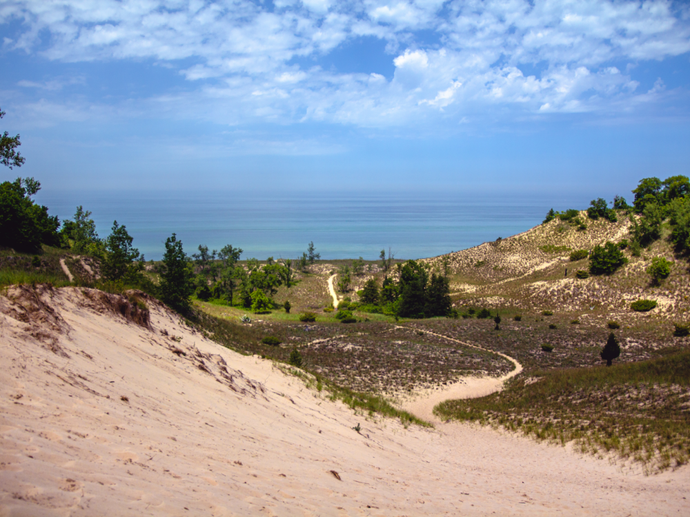 View on Lake Michigan over the vast Indiana Dunes National Park with patches of grass and bushes at a distance, one of the best beaches in the US