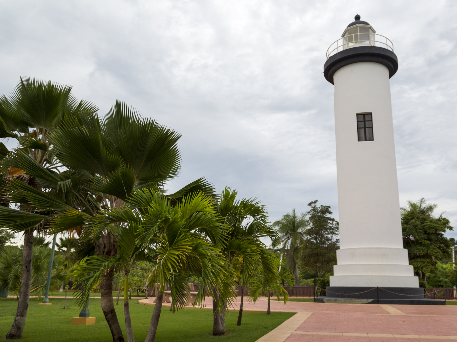A historic white lighthouse with an empty bench at Punta Higuero in Rincon, one of the best places to visit in Puerto Rico