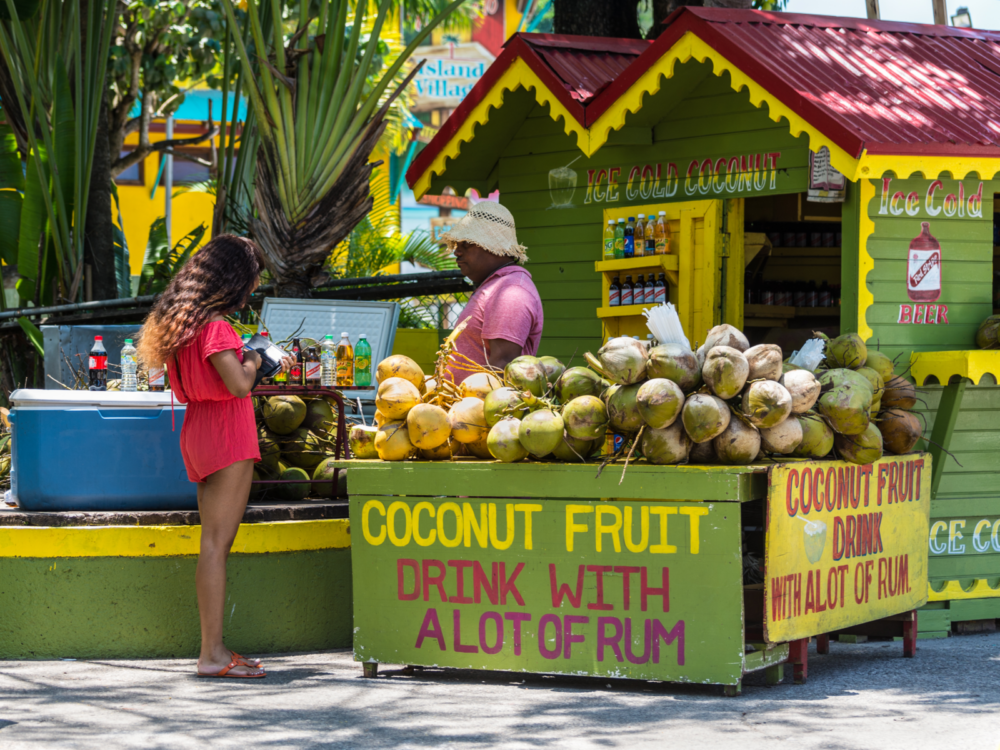 Ice cold coconut fruit drink stand with two folks interacting for a piece on the best time to visit Jamaica