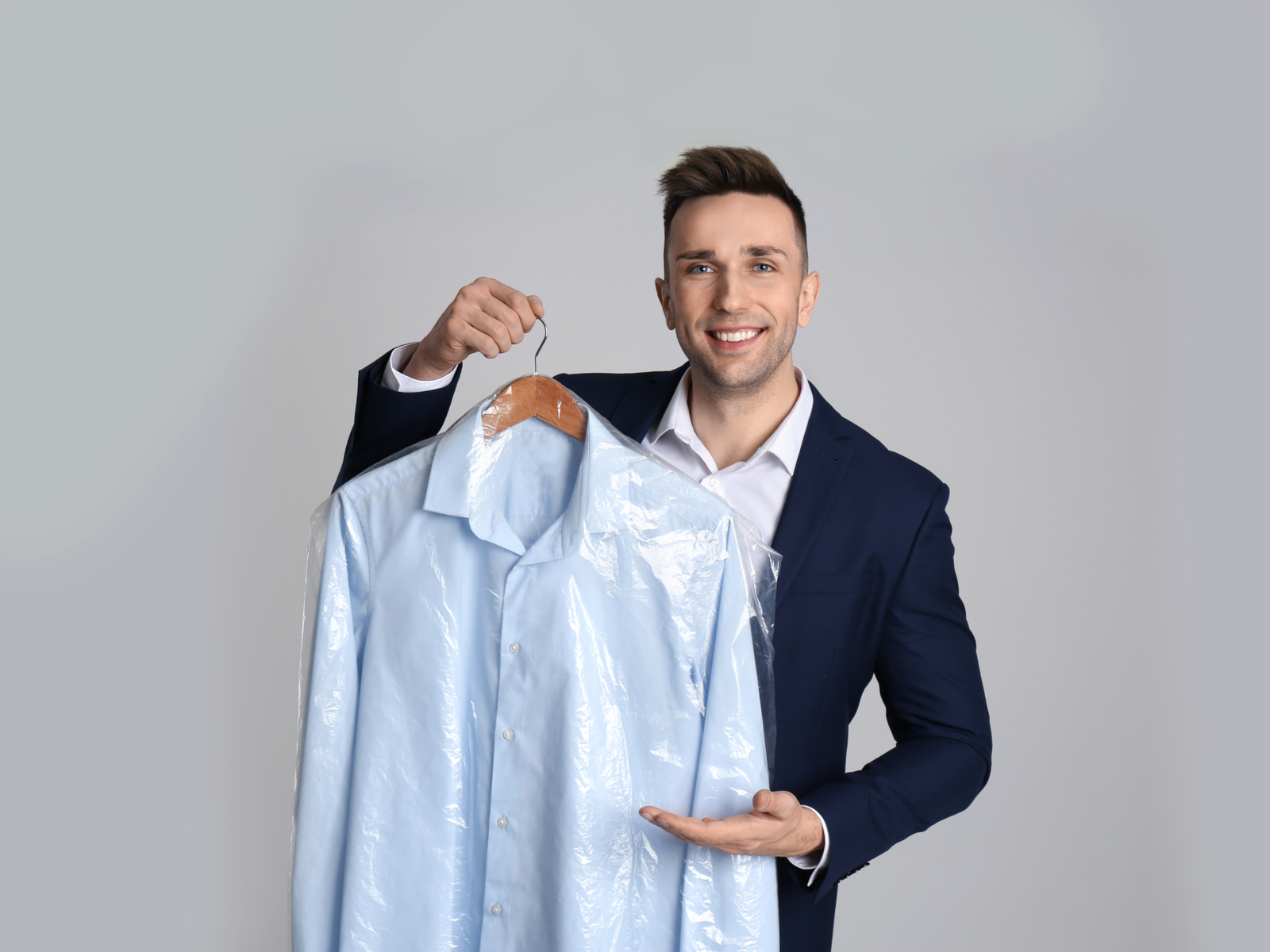 Man holding a suit in the best travel garment bag that's clear in color and smiling
