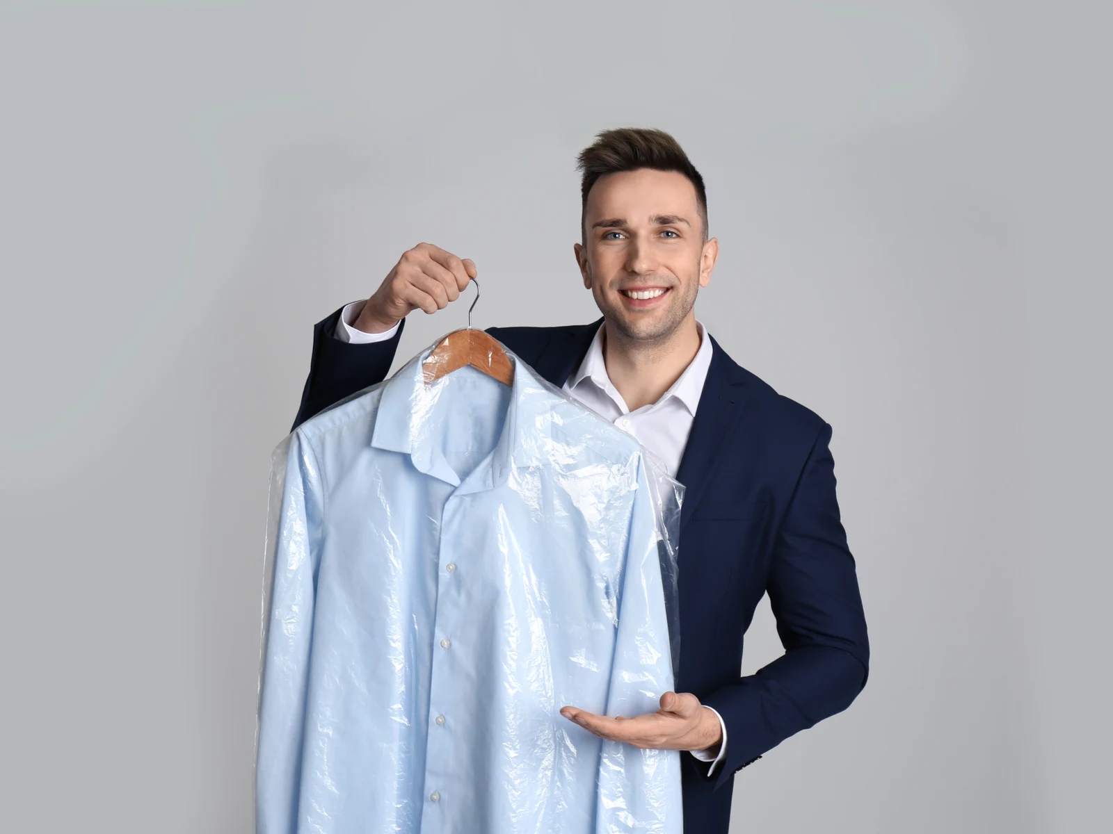Man holding a suit in the best travel garment bag that's clear in color and smiling