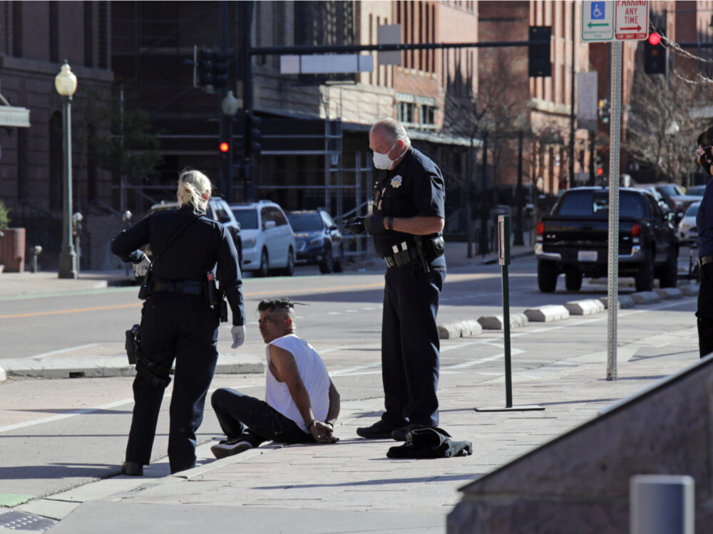 Guy handcuffed on the ground in Lodo to help answer Is Denver Safe to Visit