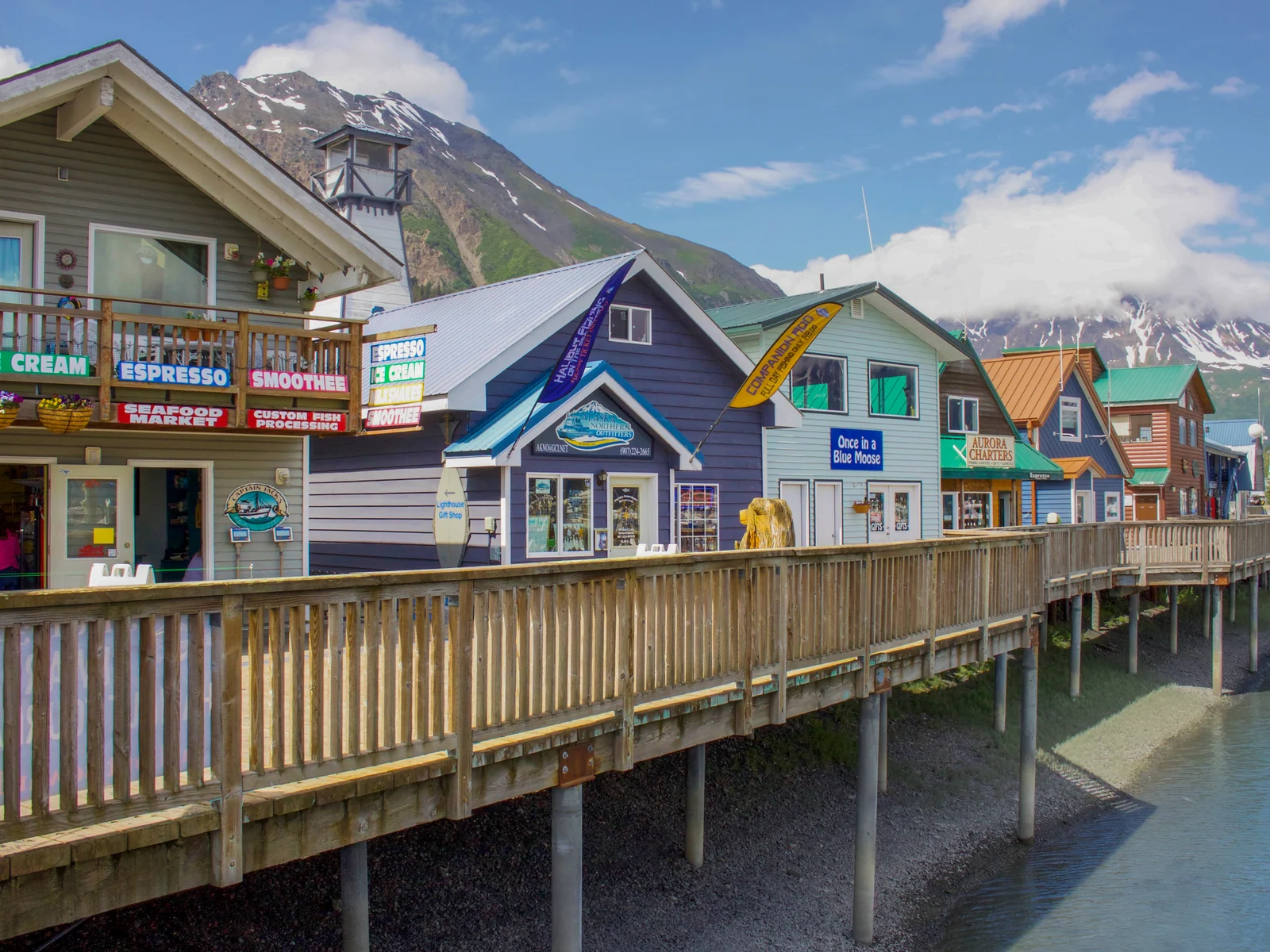 Coastal shop structures of cafes and restaurants built on a dock at Seward Harbor in Resurrection Bay in Seward, Alaska, a piece on the most beautiful cities in the US