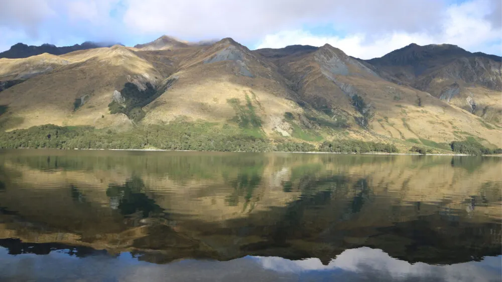 Mavora Hill's cloudy peaks, one of Lord of the Rings filming locations, reflected on the calm Mavora Lake