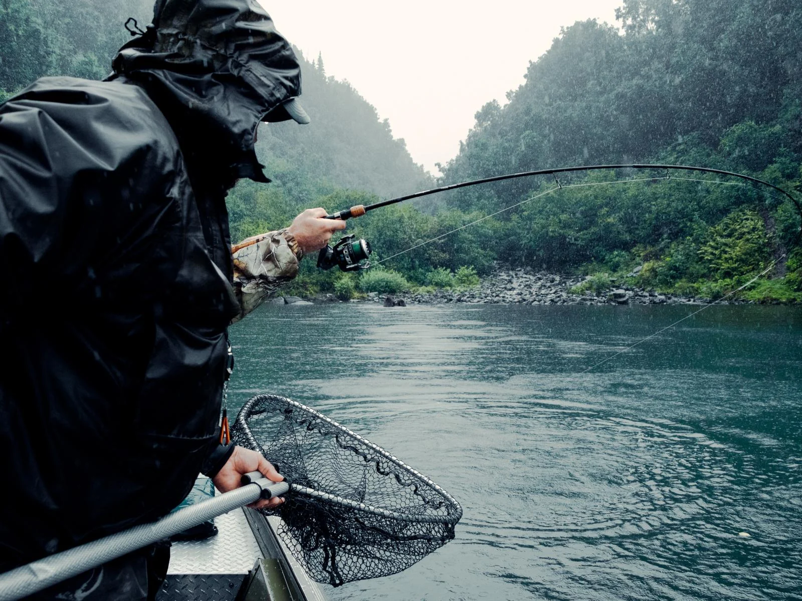 Two men fishing on a rainy day is one of the things to do in Zachar Bay Lodge, one of the best all-inclusive resorts in the U.S.