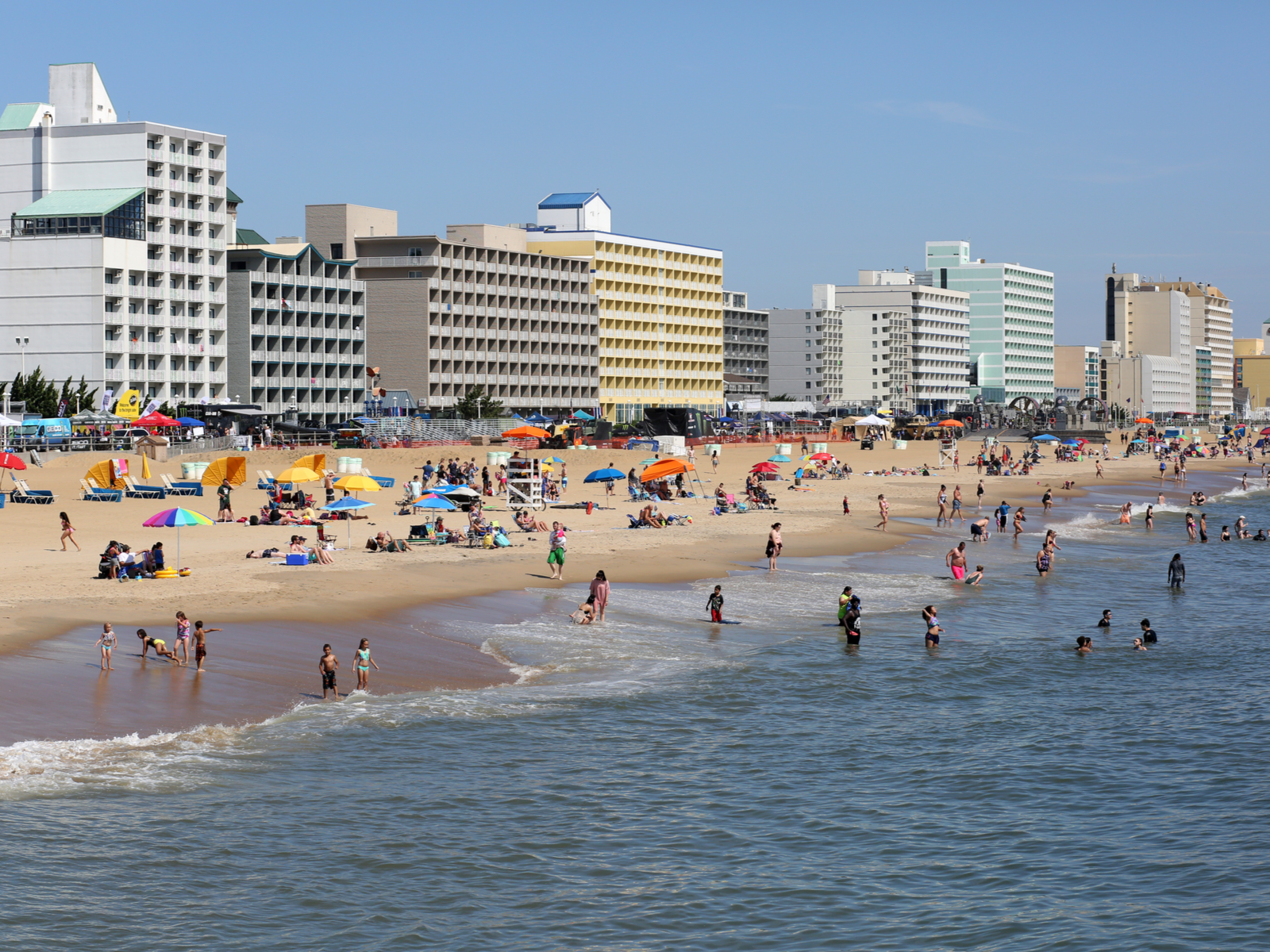 Adults and young ones enjoying a summer day at the Virginia Beach in Virginia, named as one of the best beaches on the East Coast, with resorts and hotels in background