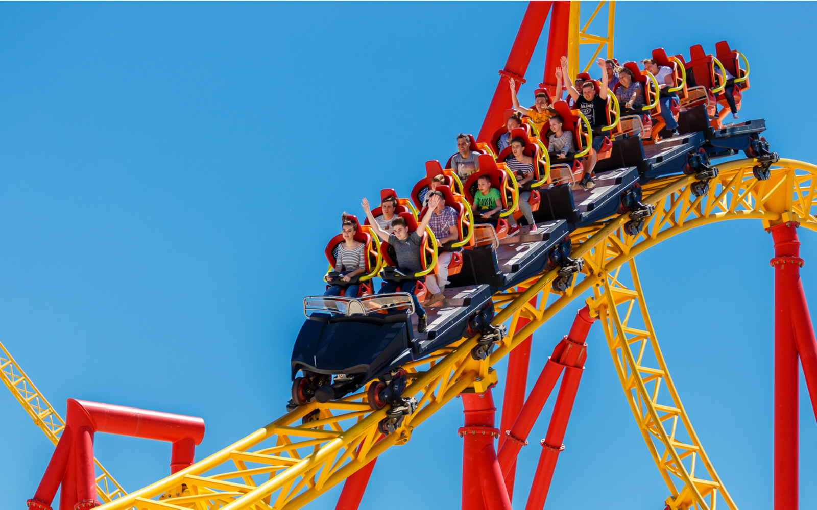 Various people riding a yellow coaster for a piece on the best roller coaster parks in the US