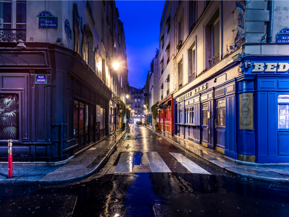 During the worst time to visit Paris, a narrow and dark alley is pictured with water on the cement and gloomy skies overhead