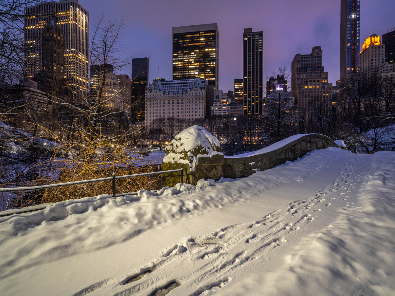 Gapstow Bridge pictured in Central Park during the Winter, the worst tim to visit, with Trump Tower and the Plaza Hotel in the background