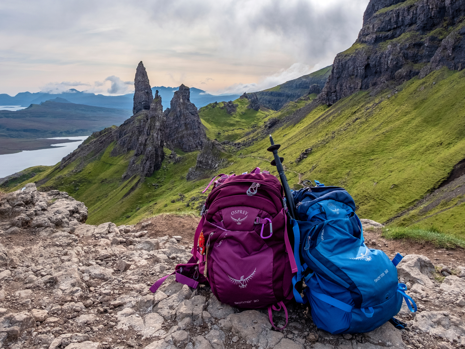 Two of the best Osprey backpacks pictured on a rocks next to a rolling grass hill at the Isle of Skye, Scotland