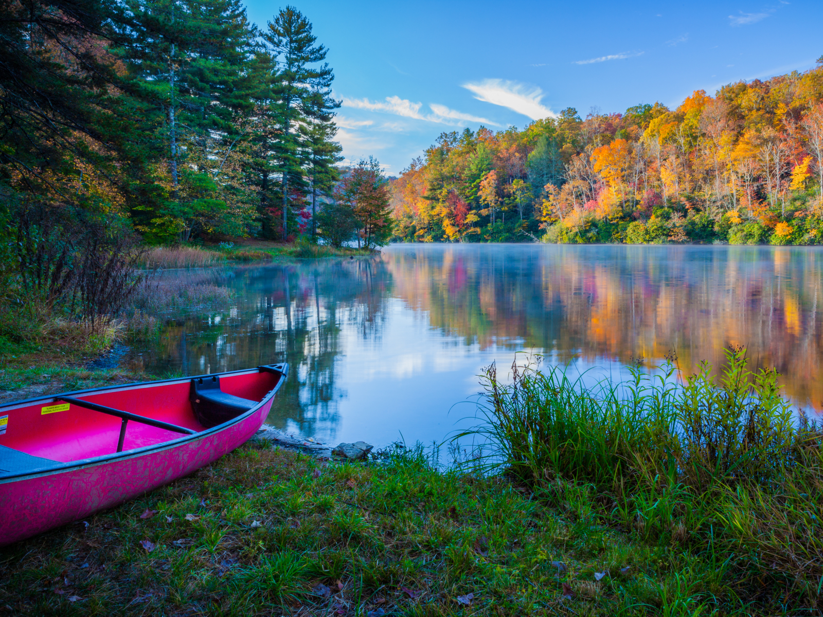Canoe on the shore of a lake during the best time to visit the smoky mountains with a bright blue sky in the background