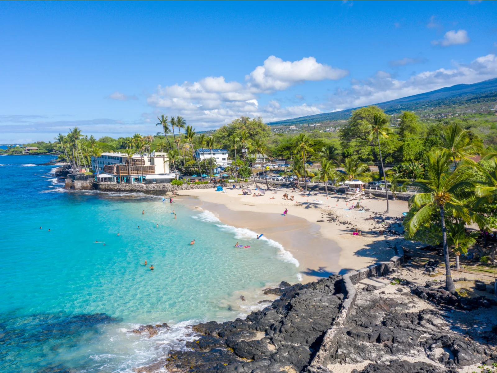 Magic Sands Beach, home to some of the best hotels in Kona, pictured on a sunny day with clear teal water