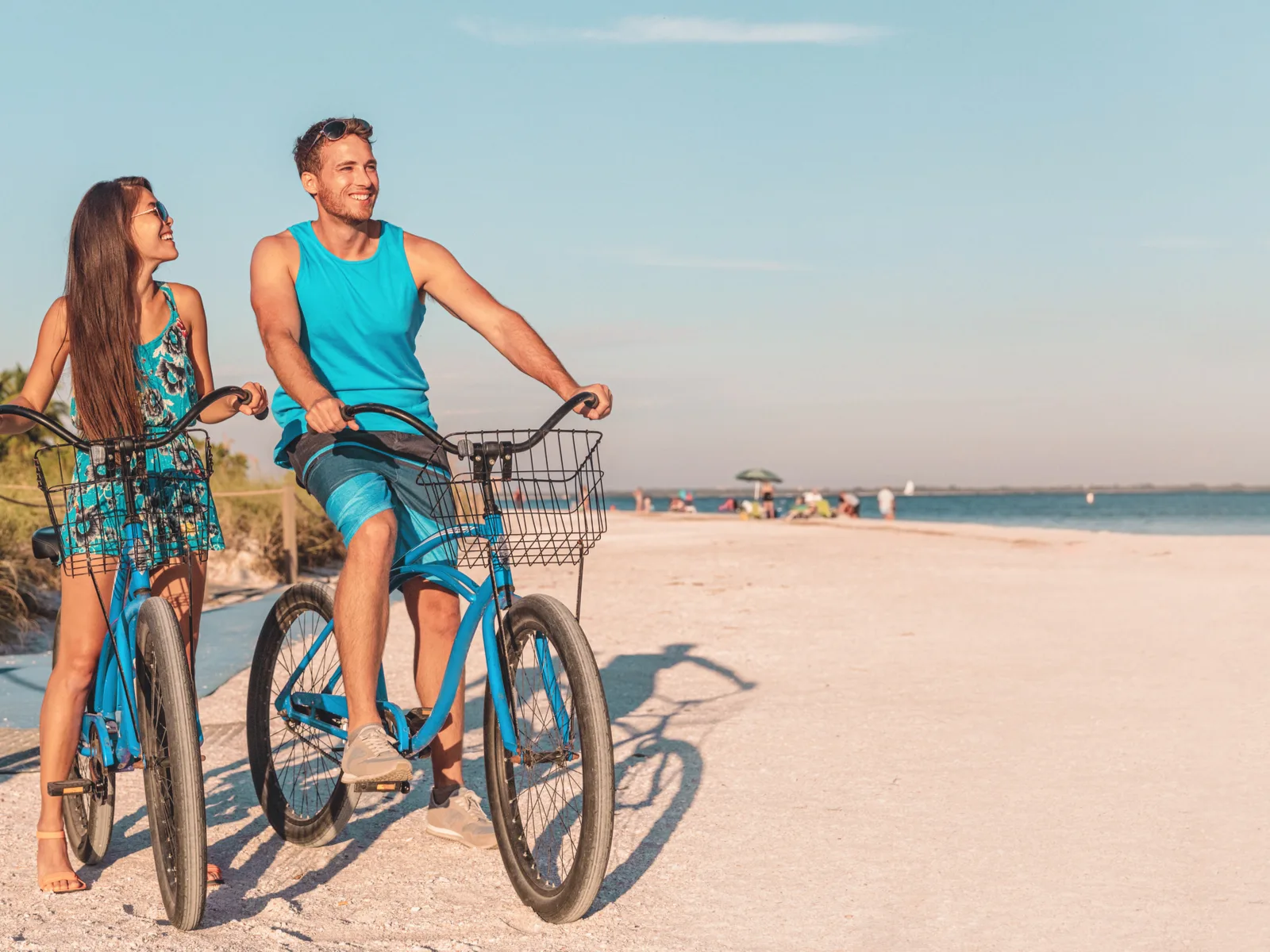 A smiling couple riding a bicycle at one of the best beaches on the East Coast