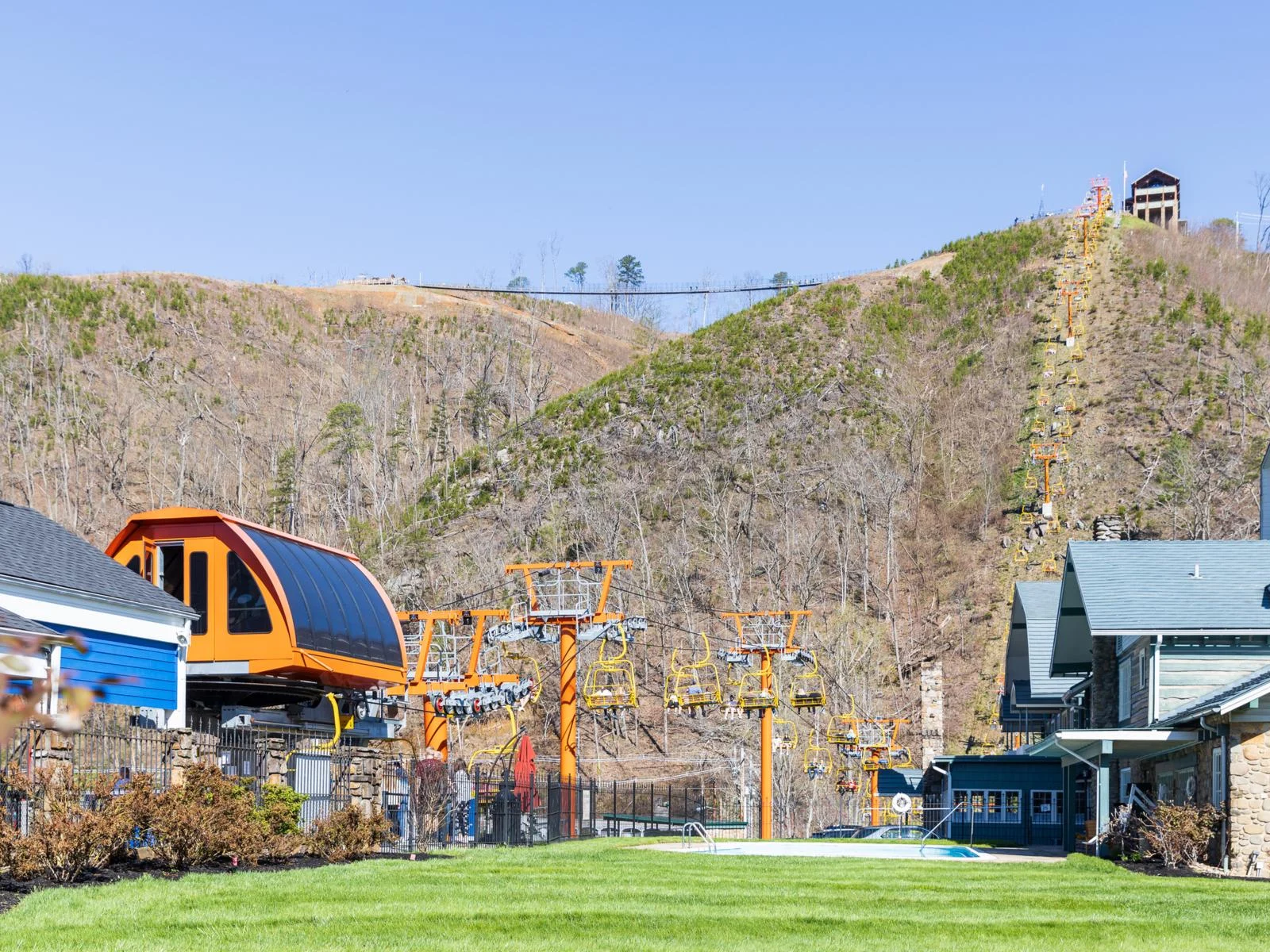 yellow chairlifts taking people to the peak of a mountain and a highly elevated suspension bridge where people are walking are one of the best things to do in gatlinburg, tennessee