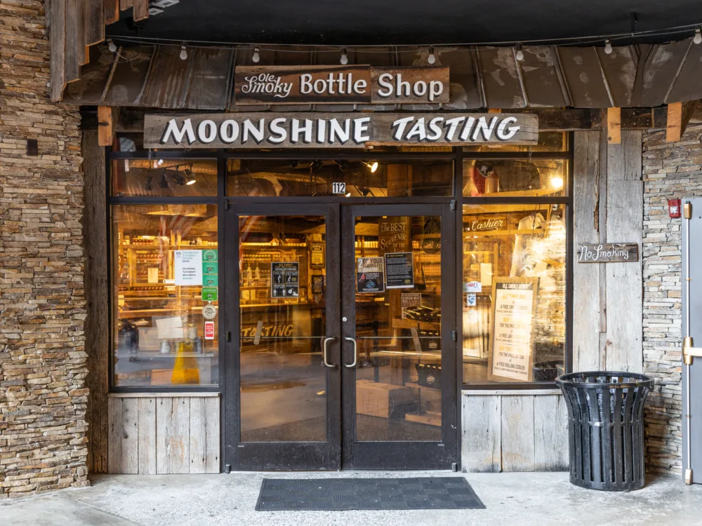 inside of ole smoky moonshine distillery, one of the best things to do in gatlinburg, tennessee, visible from an old looking store front with glass door and panels