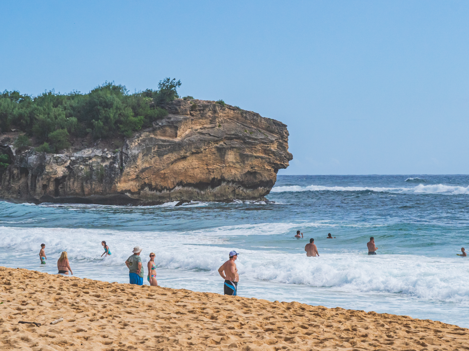 Tourists enjoy the wavy coast and the tall cliff of Shipwreck Beach, where cliff jumping here is one of the best things to do in Kauai